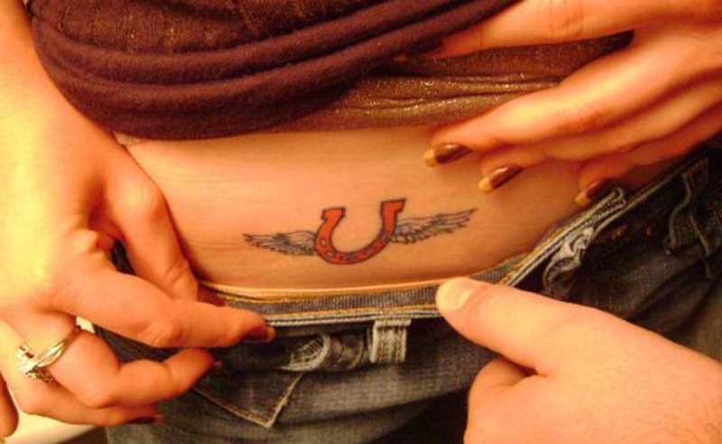 Tatuagem na barriga da menina - ferradura com asas