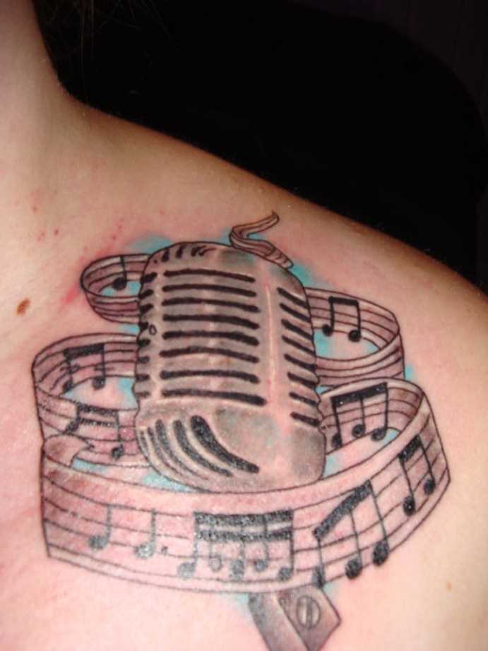 Tatuagem na clavícula menina notas e microfone