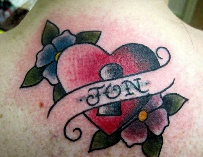 Tatuagem na coluna da menina, coração, flores, e inscrição