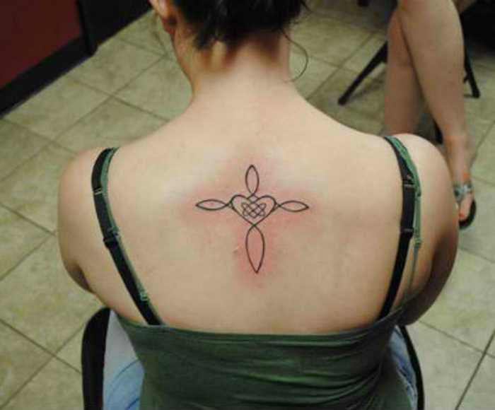 Tatuagem na coluna da menina em forma de cruz