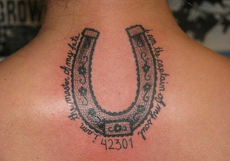 Tatuagem na coluna da menina - ferradura e inscrição