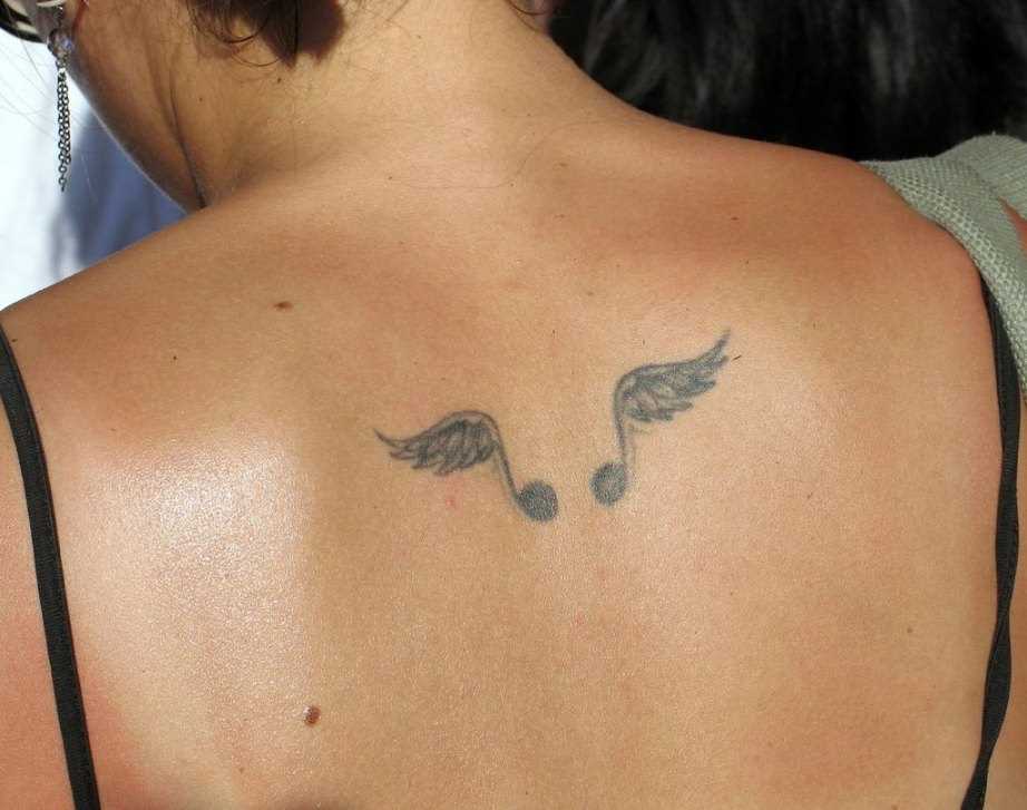 Tatuagem na coluna da menina - notas com asas