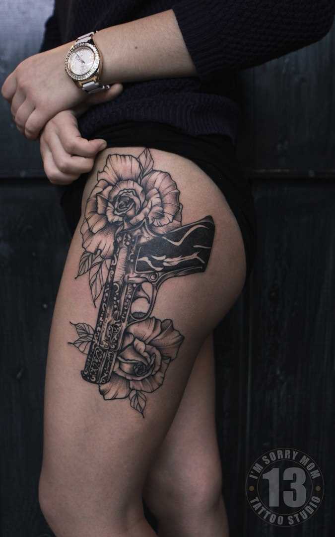 Tatuagem na coxa da menina - arma e flores