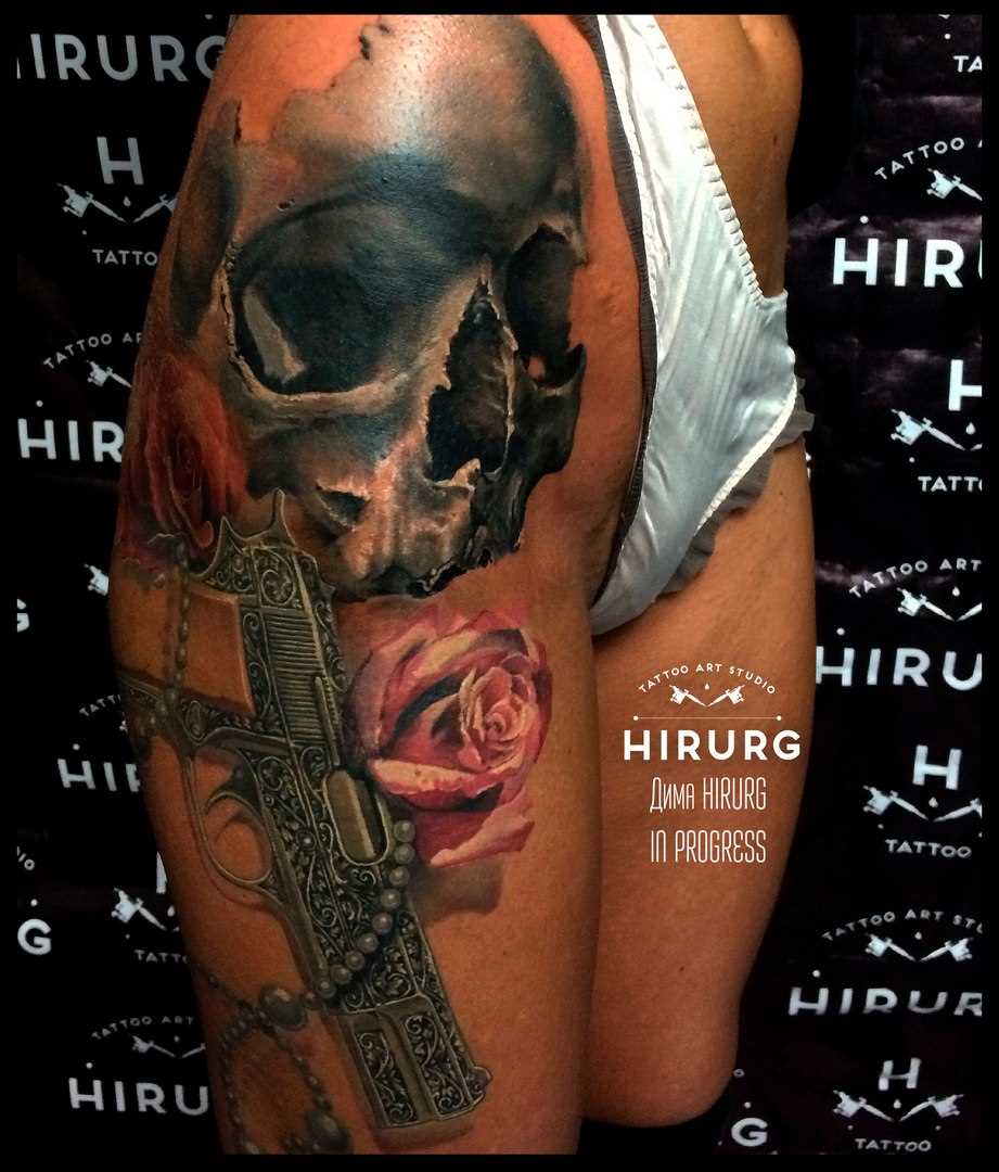 Tatuagem na coxa da menina - arma, o crânio e a rosa