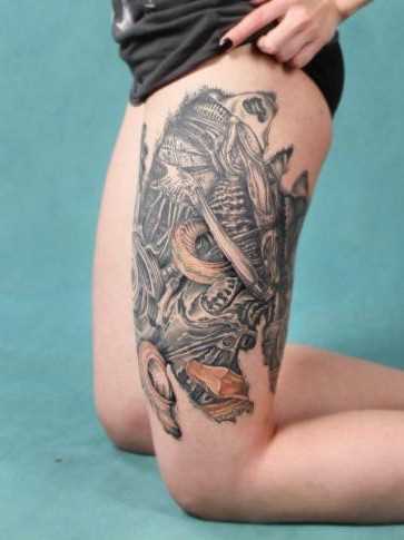 Tatuagem na coxa da menina no estilo de biomecânica