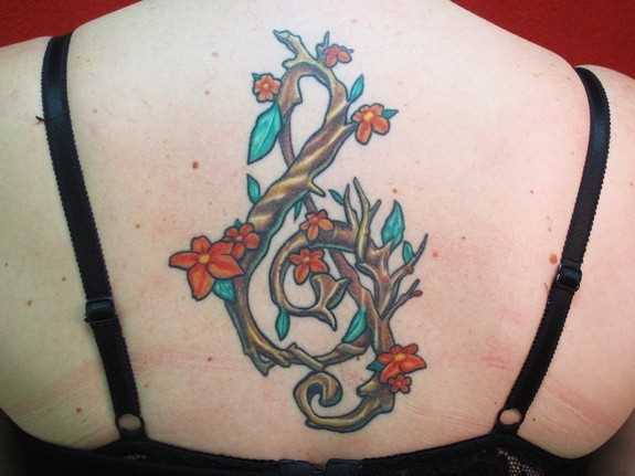 Tatuagem na espinha, as meninas - clave de sol na forma de um galho de árvore com flores