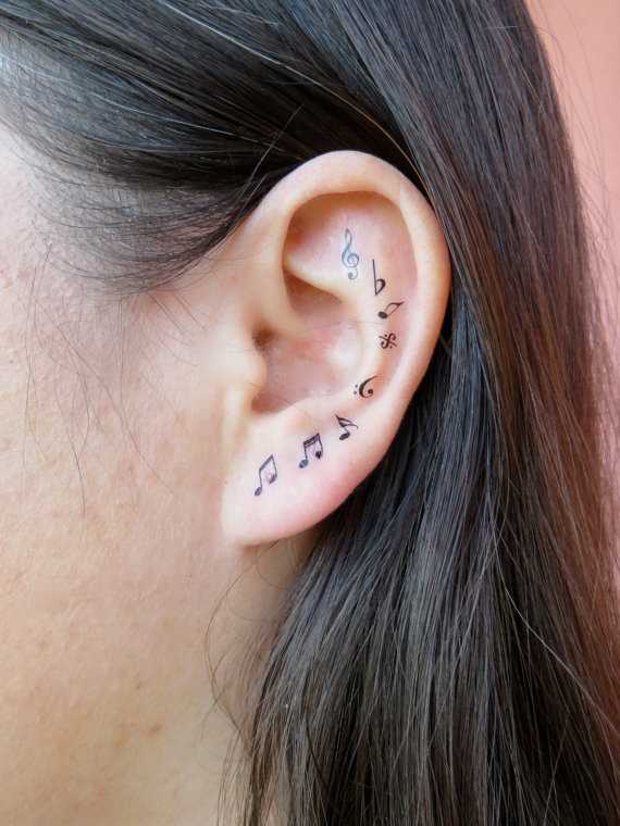 Tatuagem na orelha da menina notas e a clave de sol