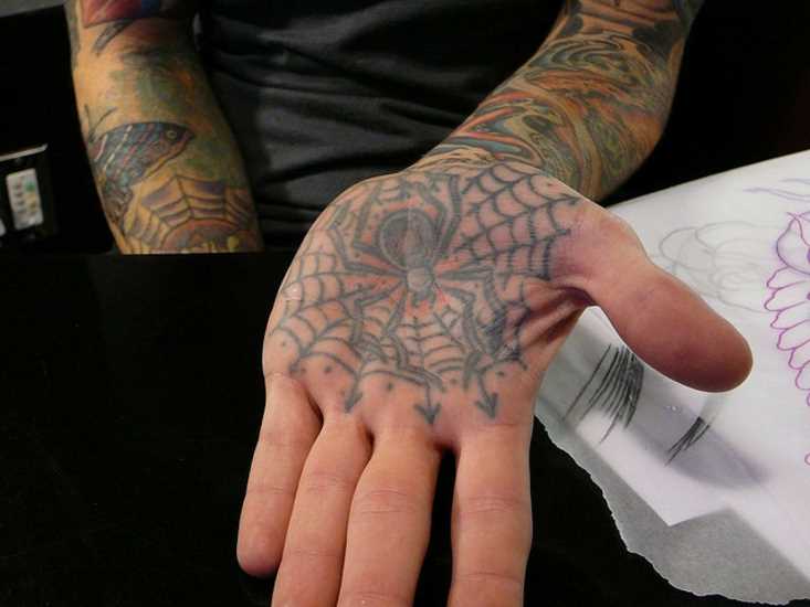 Tatuagem na palma da mão da menina - uma teia de aranha e a aranha