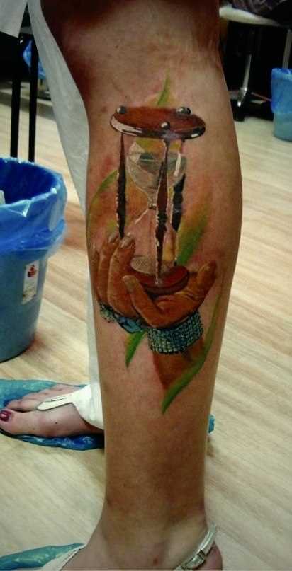 Tatuagem na perna da menina - a ampulheta e a mão