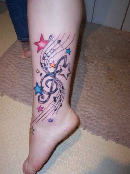 Tatuagem na perna da menina - clave de sol, estrelas e notas