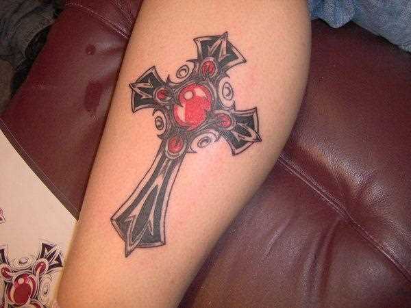 Tatuagem na perna da menina - cruz com pedras vermelhas