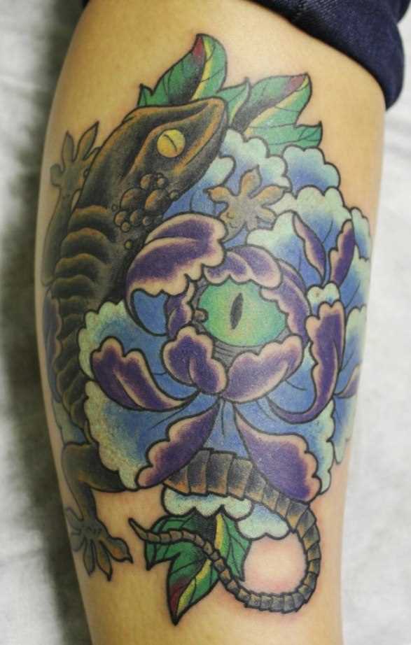 Tatuagem na perna da menina em forma de lagarto e da flor