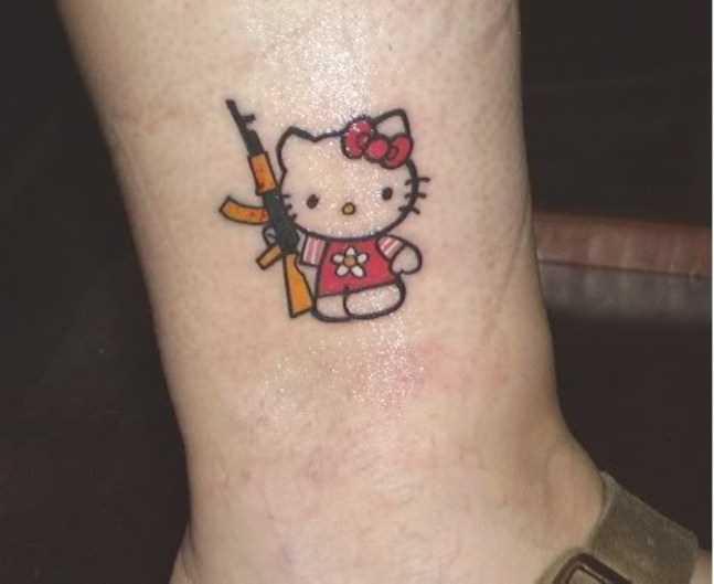 Tatuagem na perna da menina - gatinho com uma arma