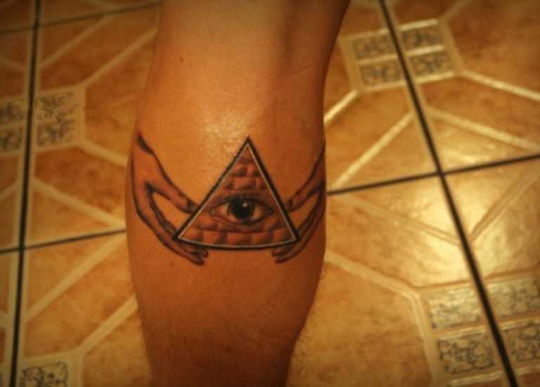 Tatuagem na perna de um cara - a pirâmide com o olho em mãos