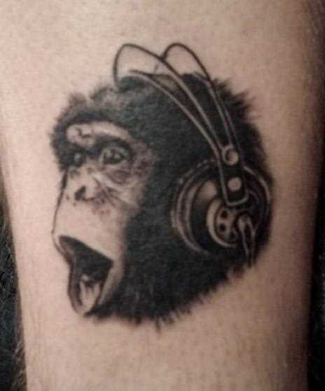 Tatuagem na perna de um cara de macaco em fones de ouvido
