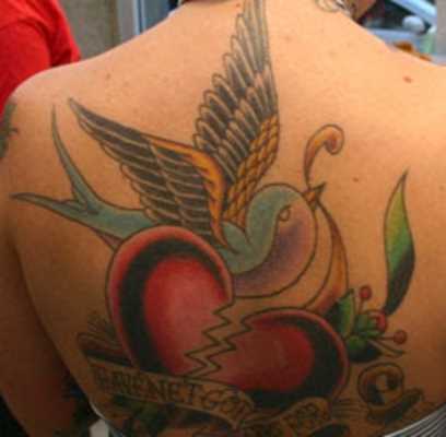 Tatuagem nas costas da menina - um coração partido, a legenda e a andorinha