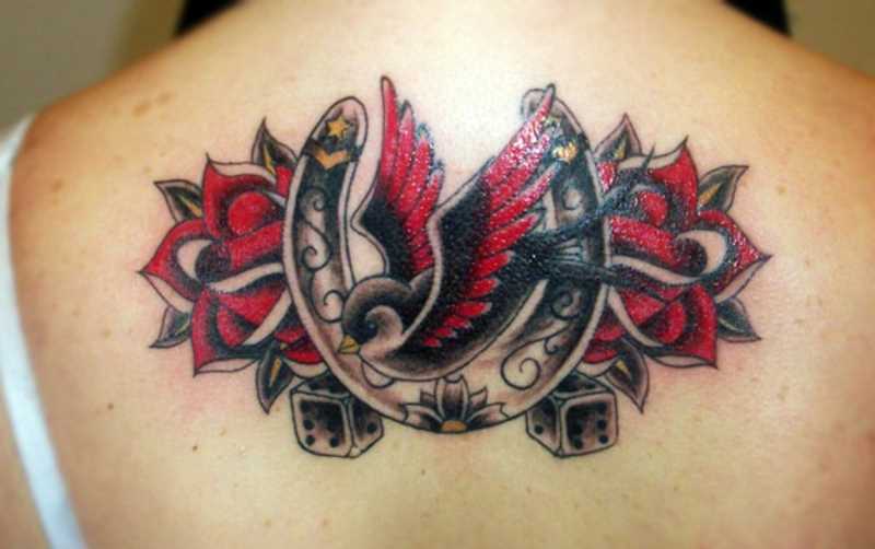 Tatuagem nas costas de uma menina - a ferradura, a andorinha, a rosa e o dado
