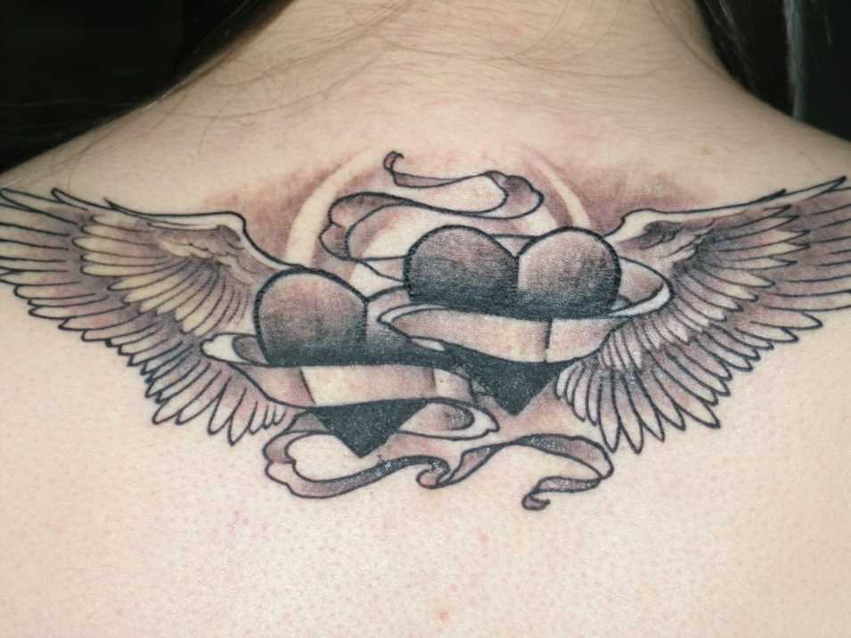 Tatuagem nas costas de uma menina de coração com asas