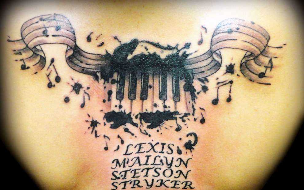 Tatuagem nas costas de uma menina notas, teclas de piano e inscrição