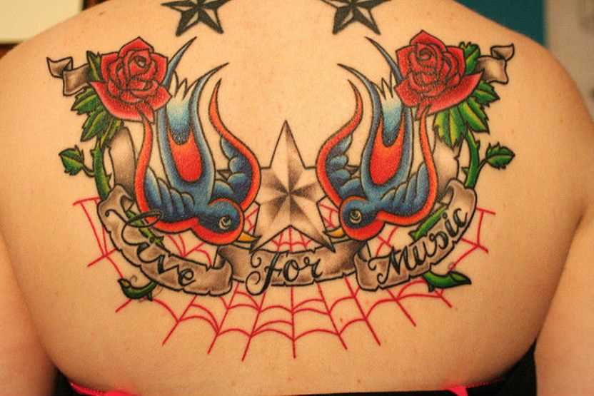 Tatuagem nas costas de uma menina - uma teia de aranha, andorinhas, a rosa, a estrela e a inscrição