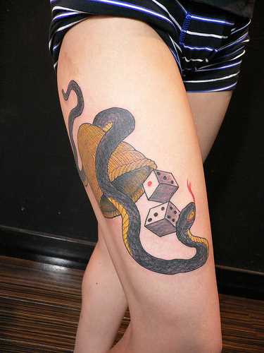Tatuagem nas coxas da menina - a serpente e o dado