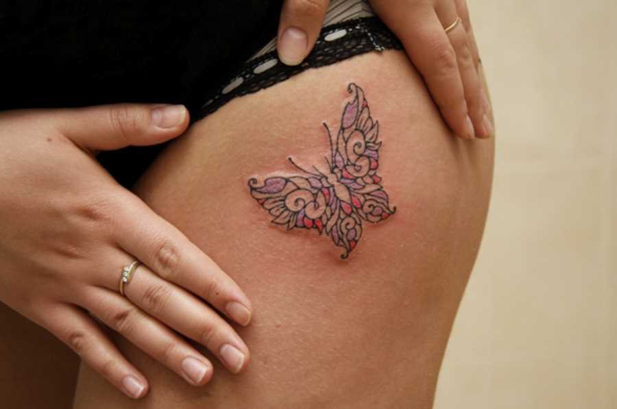 Tatuagem nas coxas da menina como uma borboleta