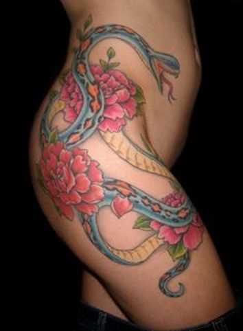 Tatuagem nas coxas da menina de cobra e de flores