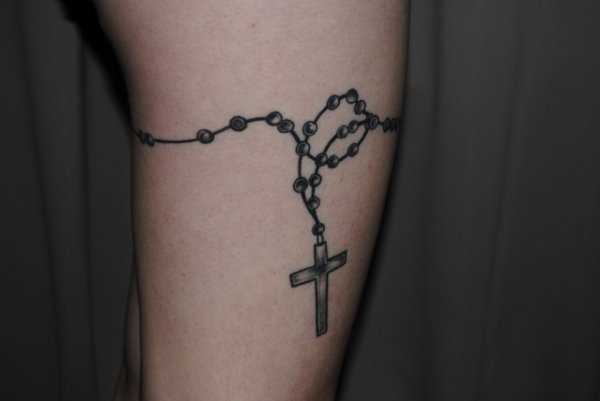 Tatuagem nas coxas da menina - um colar com uma cruz