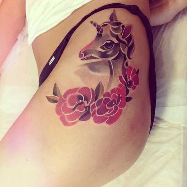 Tatuagem nas coxas da menina - um unicórnio e flores