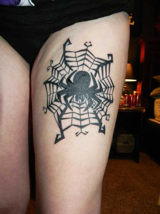 Tatuagem nas coxas da menina - uma teia de aranha e a aranha