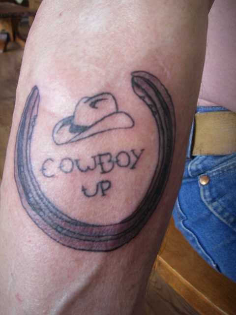 Tatuagem no antebraço cara - de- ferradura, chapéu de cowboy e inscrição