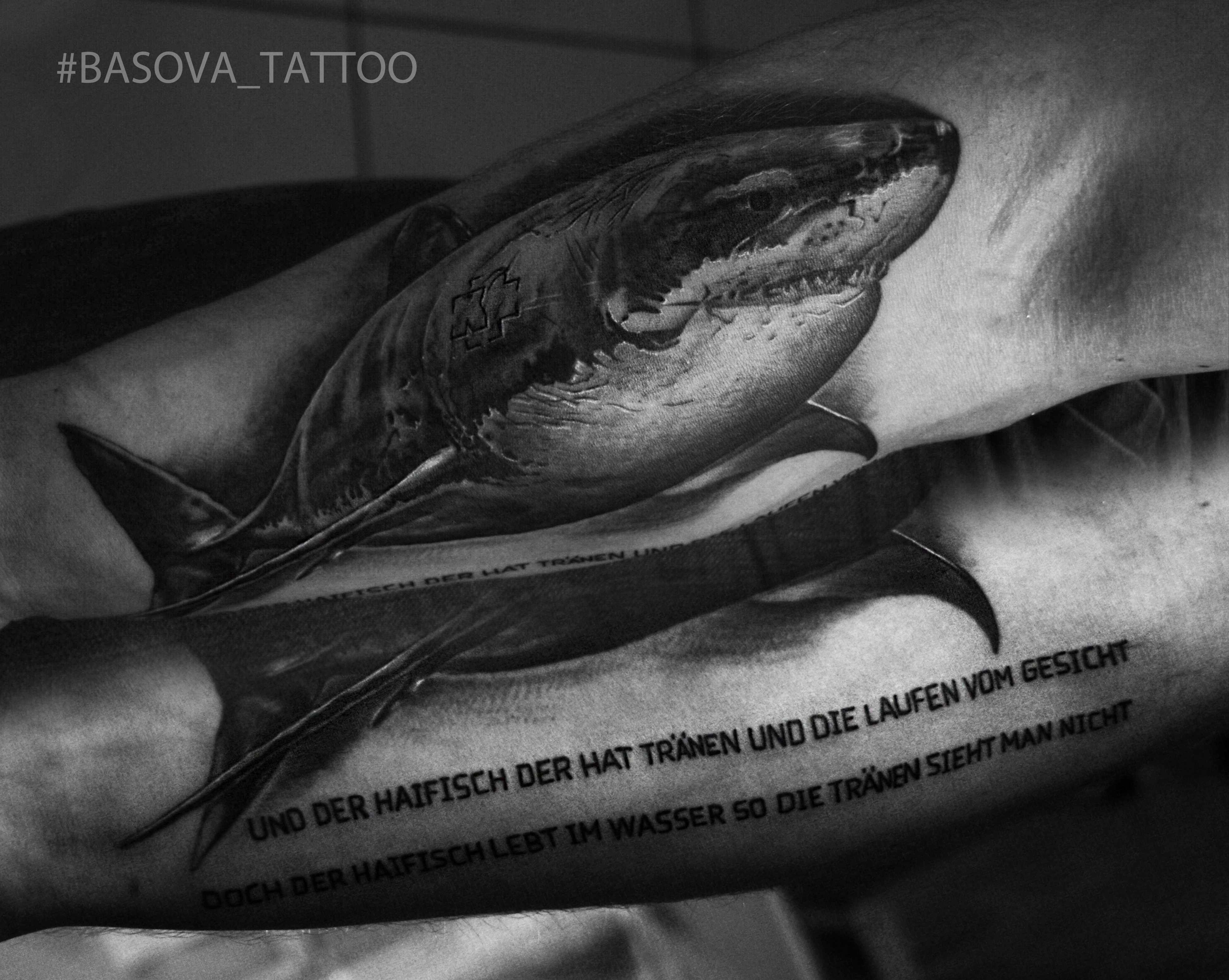 Tatuagem no antebraço cara de tubarão e o texto de uma canção de Ramstein