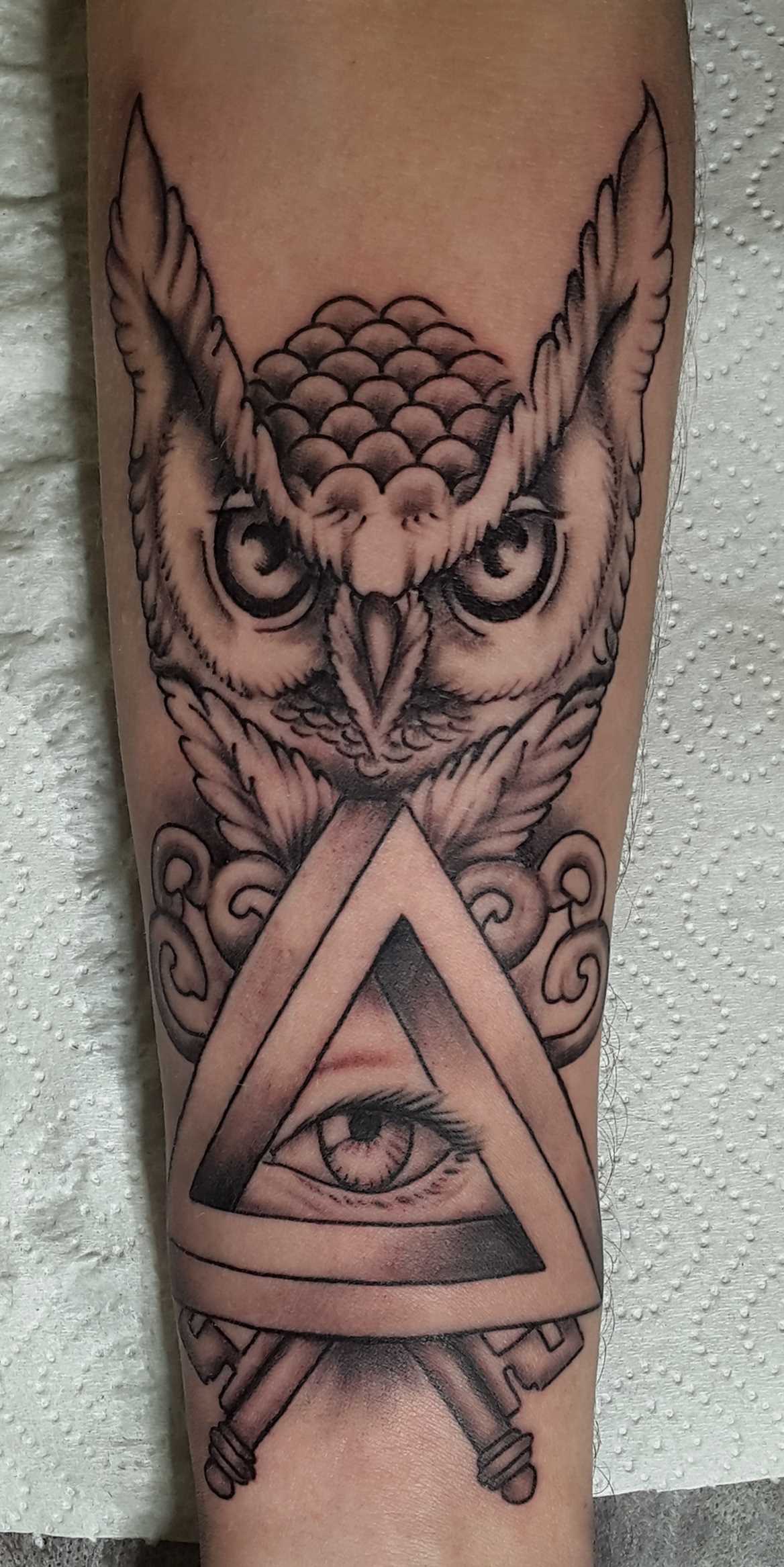 Tatuagem no antebraço da menina - a coruja e o olho no triângulo,