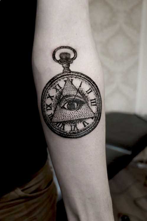 Tatuagem no antebraço da menina - a pirâmide com o olho e relógios