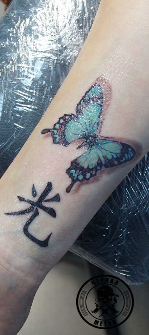 Tatuagem no antebraço da menina - borboleta e o hieróglifo