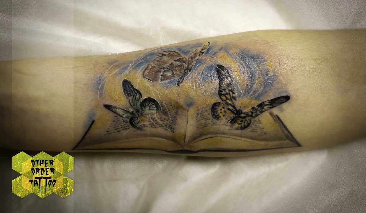 Tatuagem no antebraço da menina - borboleta e o livro