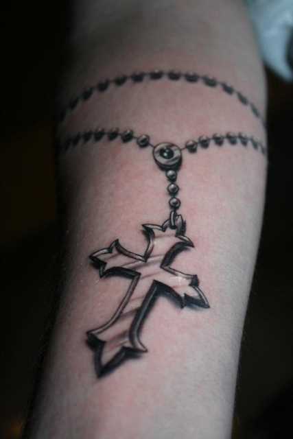 Tatuagem no antebraço da menina - um colar com uma cruz