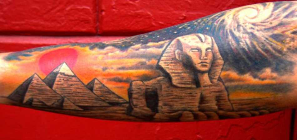 Tatuagem no antebraço de um cara em formato de pirâmides e da esfinge