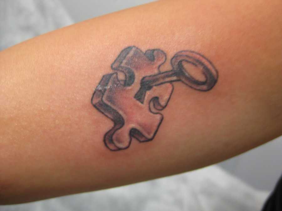 Tatuagem no antebraço de uma menina de quebra - cabeça com lite speed ® furo e a chave