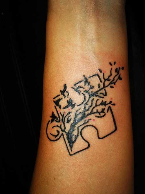 Tatuagem no antebraço de uma menina de quebra - cabeça com o ramo de uma árvore