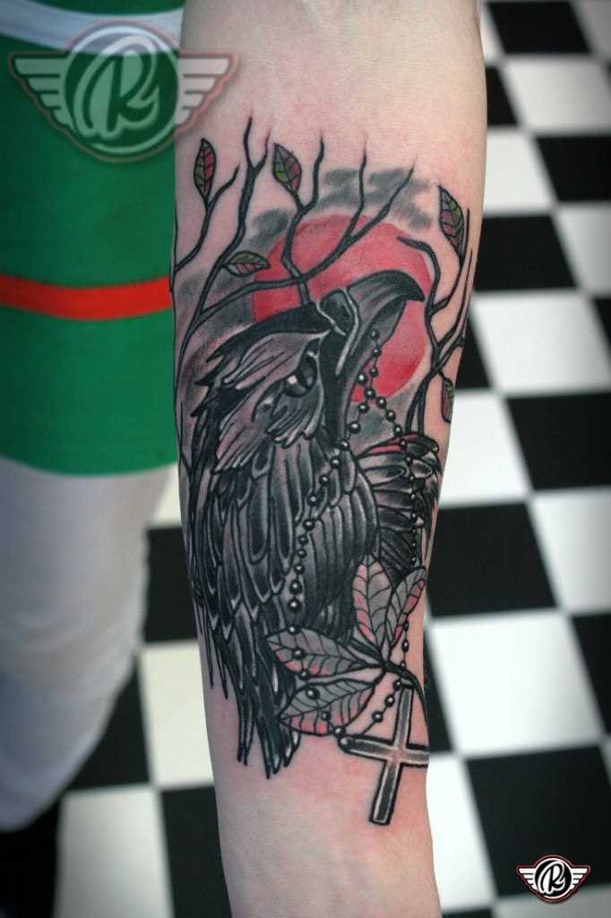 Tatuagem no antebraço do cara - o corvo com a cruz