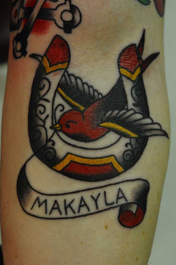 Tatuagem no antebraço meninas - ferradura, a andorinha e a inscrição