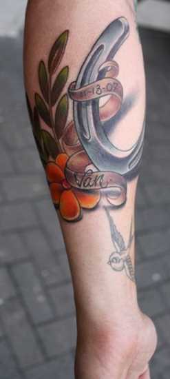 Tatuagem no antebraço meninas - ferradura, a flor e a inscrição
