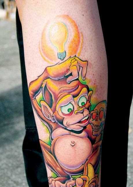 Tatuagem no antebraço para o homem - macaco com uma banana, um crânio e uma lâmpada