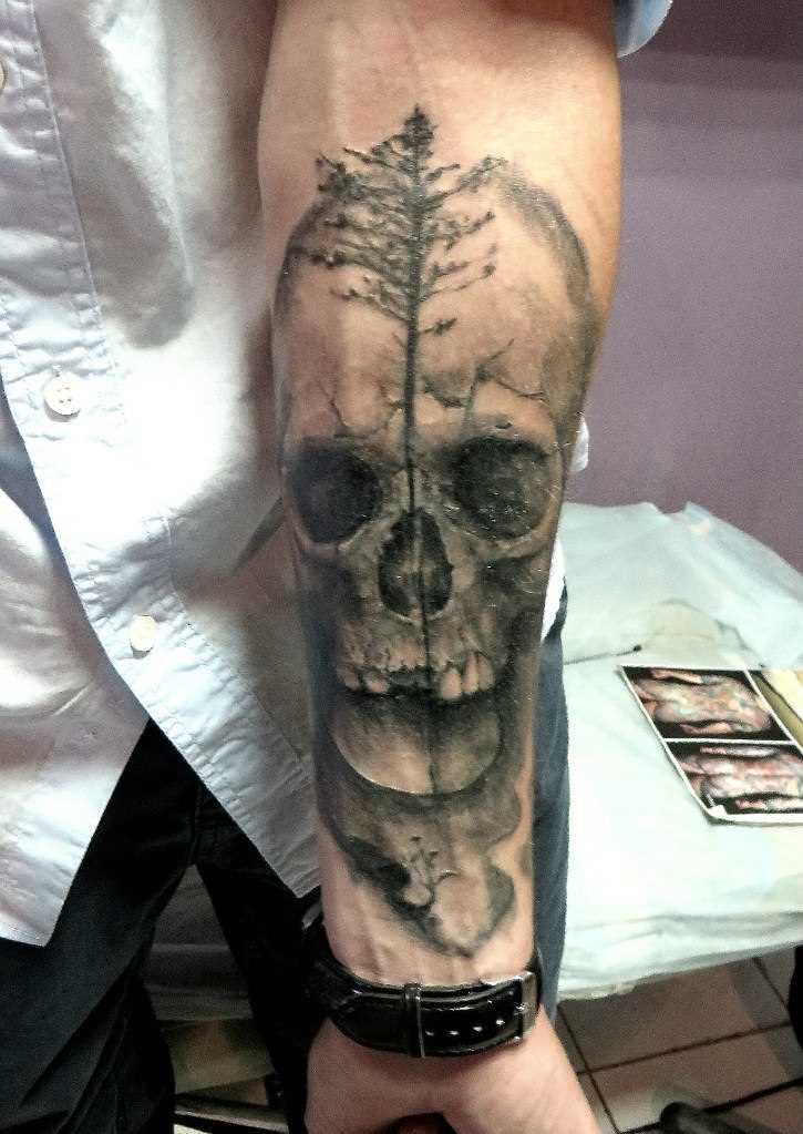 Tatuagem no antebraço tenha uma cara de crânio e a árvore