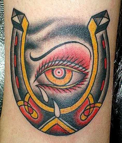 Tatuagem no braço de um cara - de- ferradura e olho