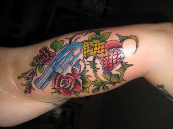 Tatuagem no braço de uma menina - uma pistola e rosas