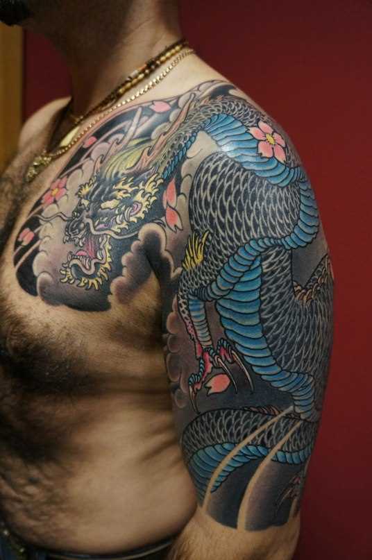 Tatuagem no braço e no peito de um cara em estilo japonês - dragão