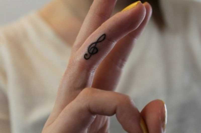 Tatuagem no dedo de uma menina - clave de sol