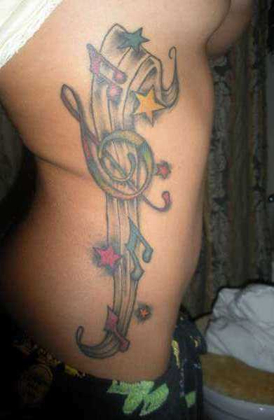 Tatuagem no lado da menina - as notas da clave de sol e as estrelas